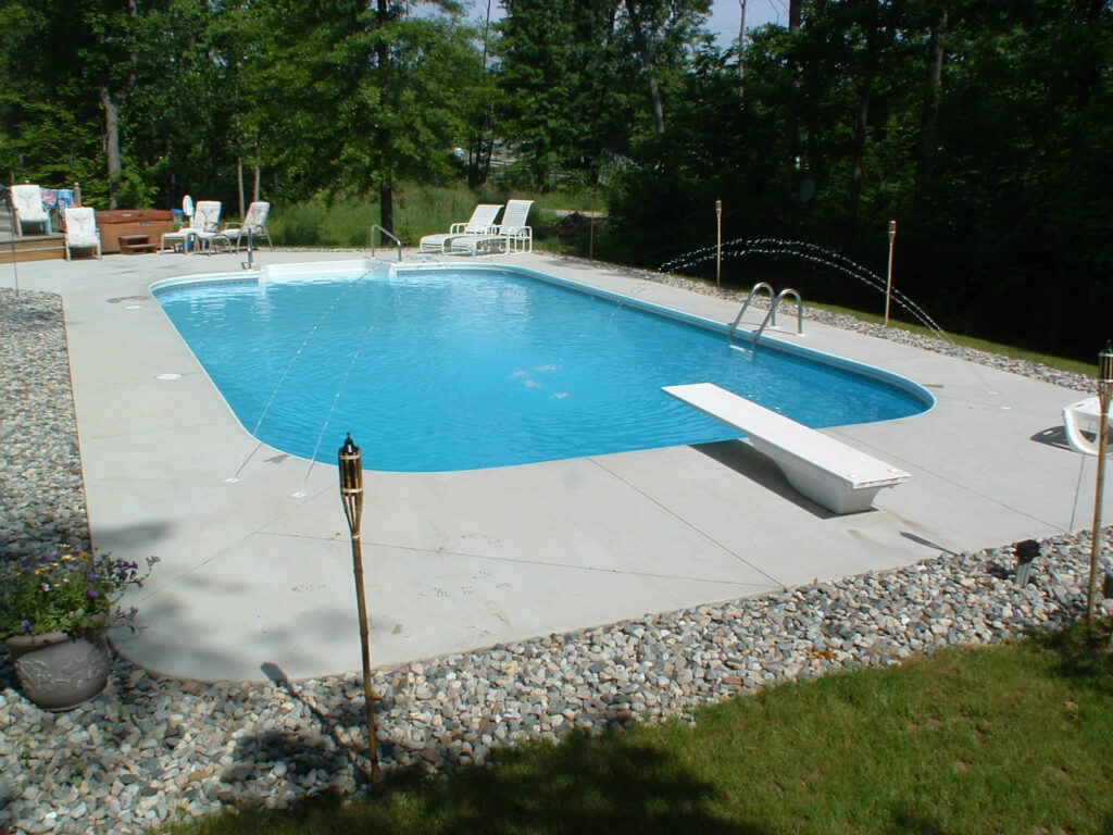 inground pool with diving board and cement coping