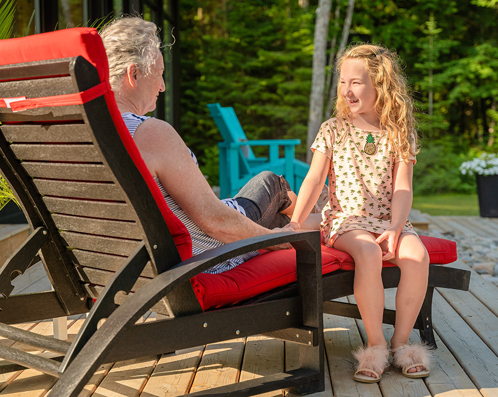 girl and grandmother sit in cr plastic patio furniture lounge by pool