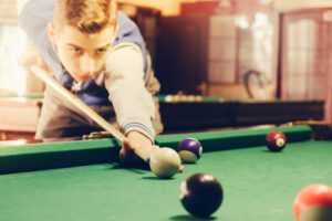 young teen plays family-friendly games on a pool table